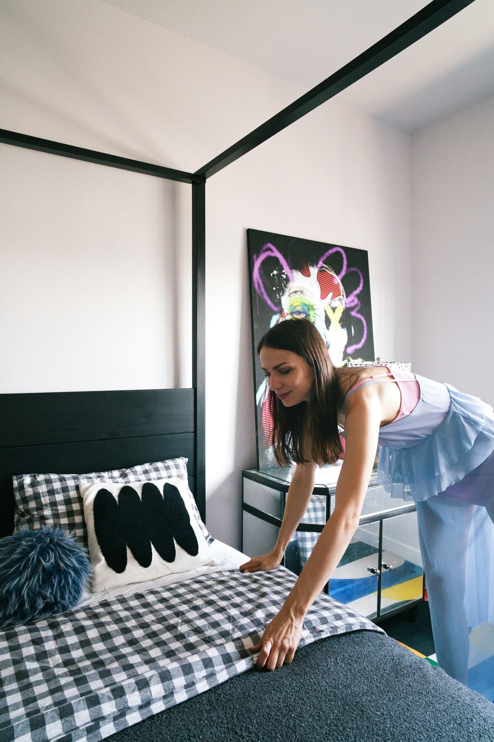Woman making the bed and smoothing linens for a guest-ready rental