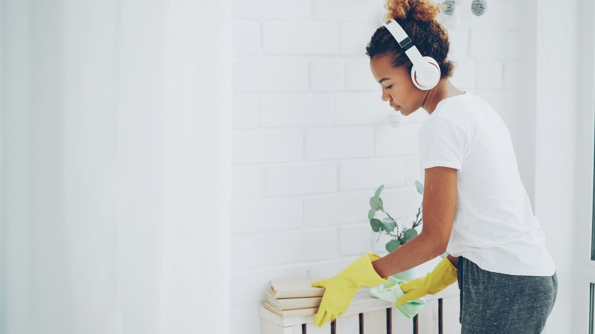 Young woman wiping a shelf with gloves during a post-renovation dust-down cleanup